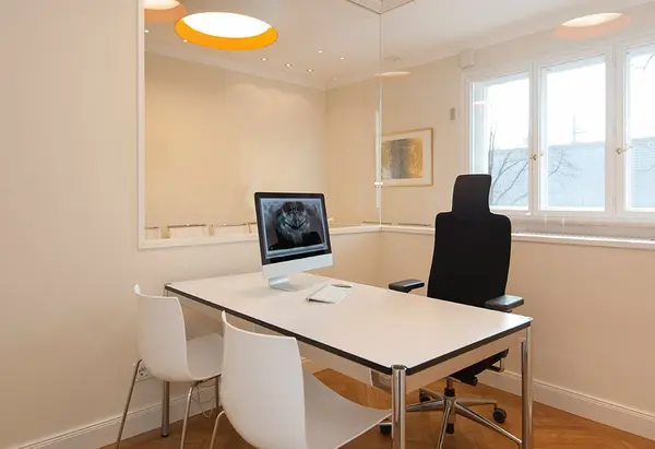 Modernes Zahnarzt-Beratungszimmer mit Schreibtisch, Monitor und Röntgenbild.