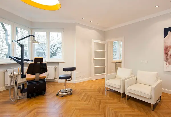 Heller, moderner Zahnarztpraxisraum mit Behandlungsstuhl, Wartebereich und Parkettboden.